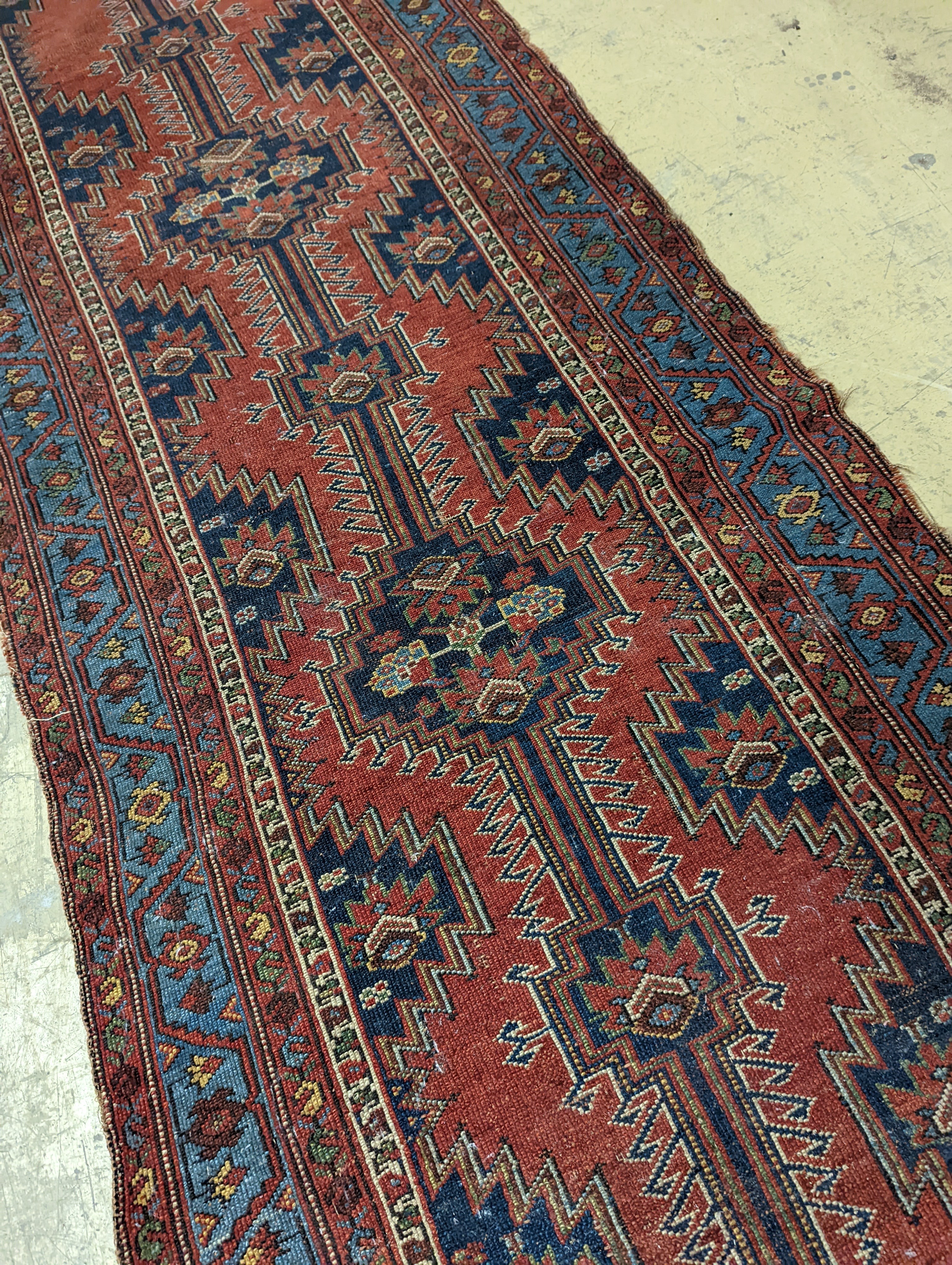 An antique Caucasian red ground runner, 380 x 100cm